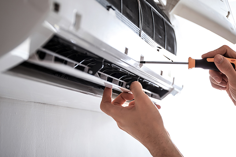 Electrician repairing air conditioner indoors.